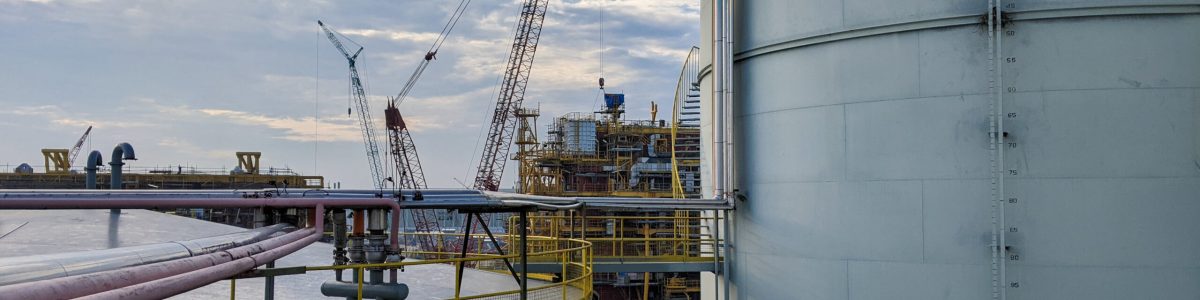 Oil storage tanks in an industrial area with the background of the oil rig construction process with blue sky background.